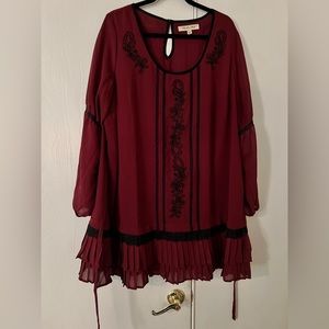 Burgundy tunic with black accents and pleated along the bottom